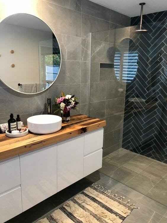 pilkas vonios kambarys su natūraliomis plytelėmis